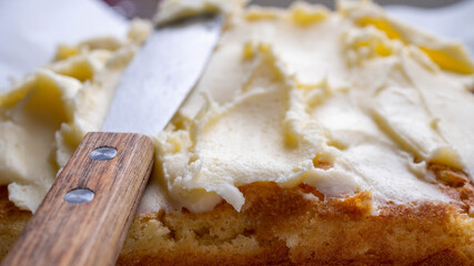 spreading buttercream icing on a sponge cake  - obrazy, fototapety, plakaty