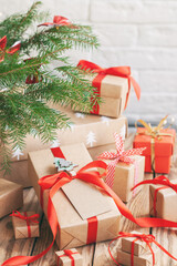 Fototapeta na wymiar Many Handmade zero waste Christmas gift boxes under fir tree on floor in room