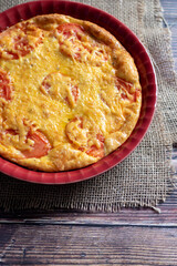 cheese and tomato crustless quiche in a red dish 