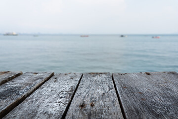 Wood plank material table - counter bar with copy space and blurred background of ocean view. Selective focus at wooden surface in center.
