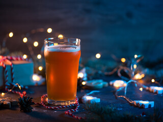 Evening Christmas composition, a glass of beer and ale on the table with gifts, garlands, cones and branches of the Christmas tree