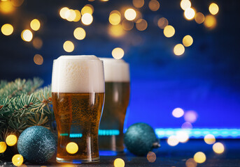 Christmas toast card, two glasses of light beer on a colored neon background with garlands and copy space