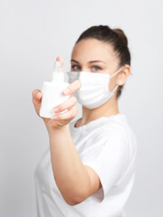 Young woman with mask holding a sanitizer spray