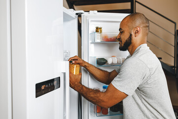 Fototapeta na wymiar African american man taking food from a fridge in his house