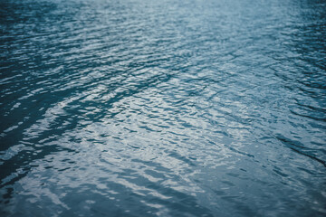 Texture of purple calm water of mountain lake. Meditative ripples on water surface. Nature minimal background of violet lake. Natural backdrop of clear dark blue water. Full frame of lake fragment.