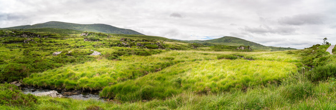 Irish countryside landscape. Valley and mountains in background. Panoramic, majestic unique view, vivid powerful colors. Part of Wild Atlantic Way. Travel magazine cover concept