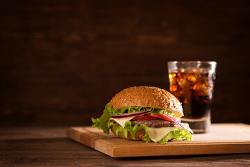 american snack with big burger and glass cola on wooden table