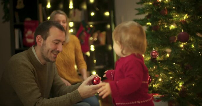 Young parents and their toddler decoration Christmas tree