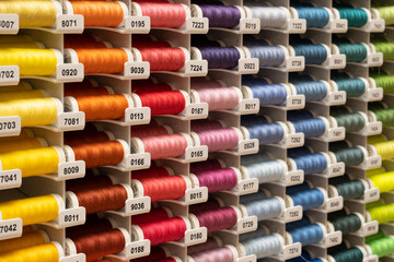 Lots of colourful threads for sewing as a rainbow in stand