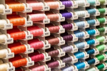 Lots of colourful threads for sewing as a rainbow in stand