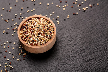 Raw, whole, unprocessed quinoa seed in a plate on a stone background. superfood product. banner,...