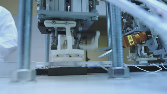 Production of medical protective face masks for air filtration. Coronavirus protection machine, covid-19. Press presses the fixing thread for ear loops or ties. Macro production line, conveyor.