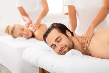 Fototapeta na wymiar Contented Spouses Enjoying Neck Massage Lying At Luxury Beauty Salon