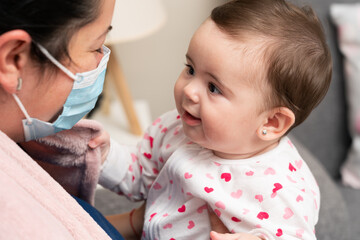 Close-up of cute baby girl playing with mother wearing mask