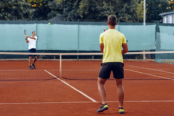 Obraz premium Two men playing tennis on clay tennis field