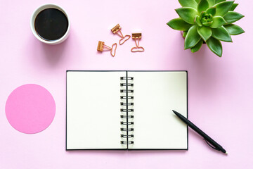 Ein geöffneter Notizblock mit einer Tasse Kaffee und Büroartikel auf einem pinken Hintergrund....