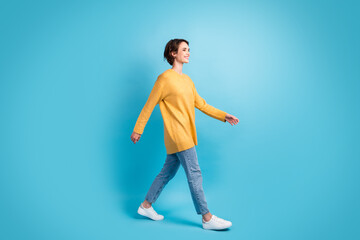 Fototapeta na wymiar Full length body size side profile photo of girl walking fast smiling isolated on bright blue color background