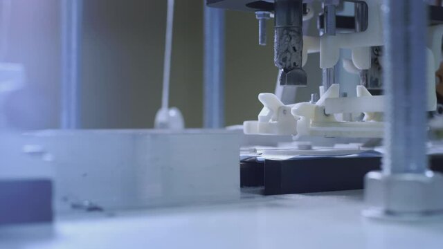 Production of medical protective face masks for air filtration. Coronavirus protection machine, covid-19. Press presses the fixing thread for ear loops or ties. Macro production line, conveyor.