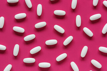 white tablets on a pink background, top view.