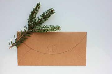 Craft envelope with heart on white background. Christmas card with christmas tree twig. Top view, copy space. 
