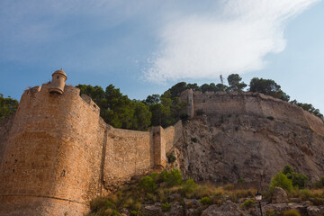 Fototapeta na wymiar Low angle of Denia's moorish castle ruins on a rocky crag overlooking the city. Alicante province, Costa Blanca, Valencian community, Spain. 