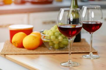 Two wine glasses with red wine on wooden kitchen counter