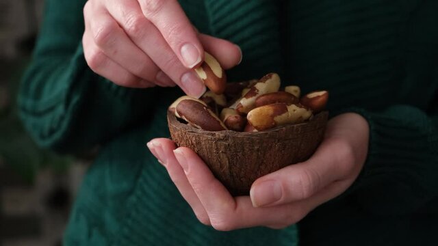 Woman eating brazil nuts. Healthy vegan vegetarian food, trendy superfood nuts