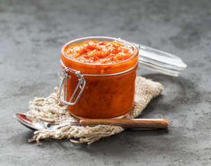Vegetable appetizer, zucchini Caviar with tomatoes, onions in a glass jar on a linen napkin on a dark background in rustic style