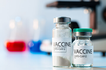Vial of Covid-19 vaccine next to a microscope