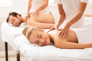 Fototapeta na wymiar Relaxed Spouses Enjoying Massage Lying On Beds At Spa Center
