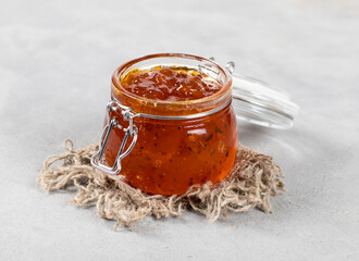 Marmalade berry, jam from sea buckthorn in a glass jar on a linen napkin light gray background in rustic style