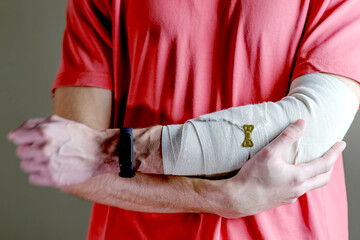 The man supports the injured hand. Primary care, the hand is tightly fixed with an elastic bandage.