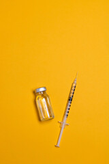 Coronavirus, flu or measles vaccine vial with syringe on yellow background, horizontal banner with copy space. Family immunization concept.