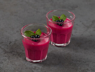 Panna cotta cream with black currant in a glass on a dark background