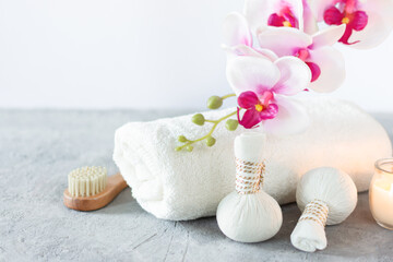 Composition with spa equipment for herbal massage and orchid with soft towel over white background.