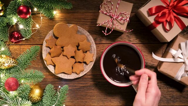 Gingerbread cookies and mug of hot cocoa on wooden table in Christmas, New Year, winter holidays atmosphere. Woman's hand stirring hot cocoa with tea spoon