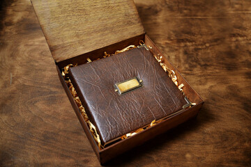 gift photo book in a leather cover in a wooden box on a wooded background. Vintage photo album.