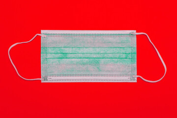 Medical face mask on a red background. Respiratory protection. Safety during a pandemic. Christmas background, coronavirus