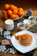 Festive table setting with vegane pancakes and tangerines