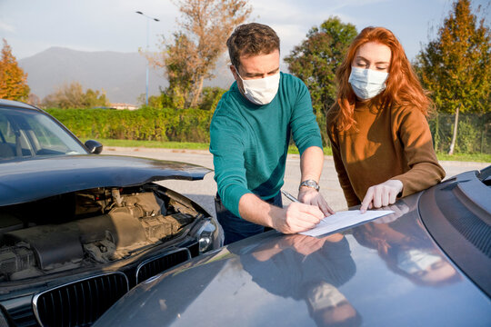 Man And Woman Filling An Insurance Car Report After Car Crash Wearing Face Mask For Corona