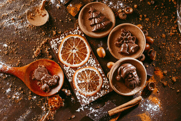 various Christmas figurines made in chocolate lie on a dark background