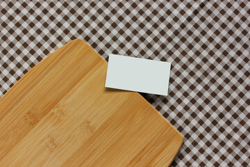 empty business card and cutting Board on a checkered tablecloth, top view.