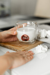  A glass of milk in the hands of the child.