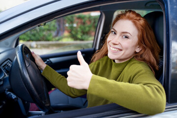 Fototapeta na wymiar Young woman at the wheel of her new car thumb up