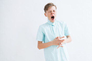 A mid shot of a tired teenage boy yawning on a white background