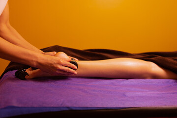 Obraz premium Hot stones massage on feet and toes of female during hot stones massage therapy, close up.