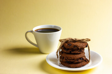 Chocolate chip cookies with a cup of coffee on a yellow background.