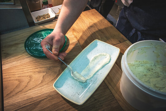 A Chef Spreading Garlic Mayonnaise On A Serving Plate.