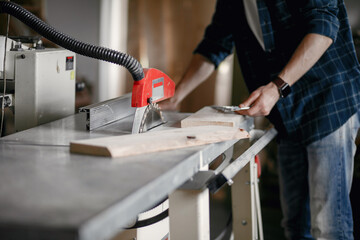 Wood cutting with circular saw. Closeup of mature man sawing lumber.