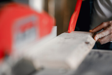 Craftsman cutting a wooden plank. Worker with wood. Man in a blue shirt.